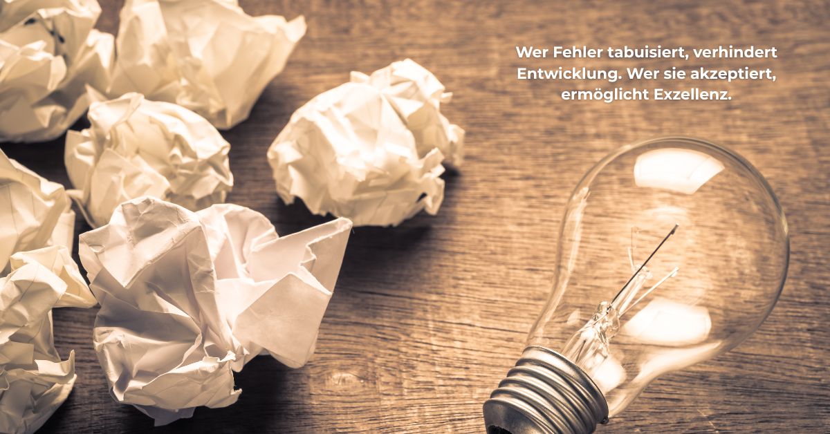 Zerknülltes Papier und Glühbirne auf Holztisch mit Zitat: „Wer Fehler tabuisiert, verhindert Entwicklung. Wer sie akzeptiert, ermöglicht Exzellenz.